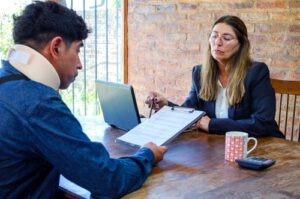 female attorney reviewing clipboard documents with injured client wearing neck brace