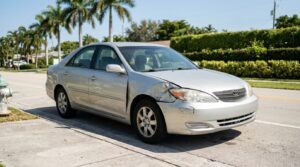 Toyota sedan with crumpled front passenger fender damage parked on roadside