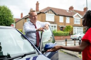 two people in heated dispute beside car door on residential street